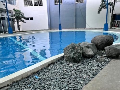 a swimming pool with rocks and blue water at Cozy Nook in the City in Manila