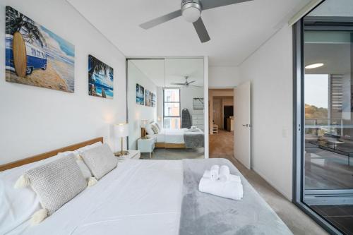 a bedroom with a white bed with two towels on it at Little Bay Haven-Stylish Coastal Apartment in Sydney
