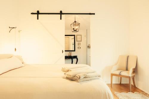 a white bedroom with a bed and a chair at Over The Road in South Bingera