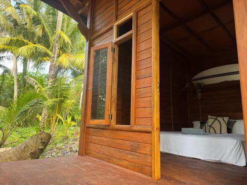 an open door of a wooden house with a bed at Diamond Island Eco Resort in Pulau Palambakbesar