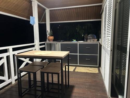 a kitchen with a table and chairs on a balcony at Le BUNGALOW CALEDONIEN DE SARRAMEA DEPAYSEMENT in Sarraméa