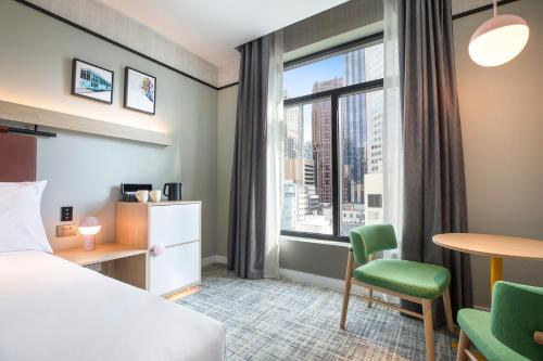 a hotel room with a bed and a desk and a window at Holiday Inn Melbourne Bourke Street Mall by IHG in Melbourne