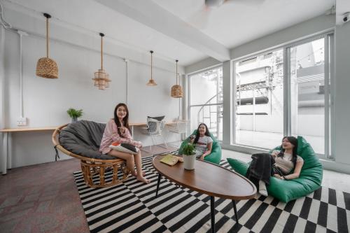 three women sitting on chairs in a living room at Unplugged at Bangrak Design Hostel in Bangkok