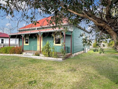 a green house with a red roof on a yard at The Settlers Cottage - In the Heart of St Helens in St Helens