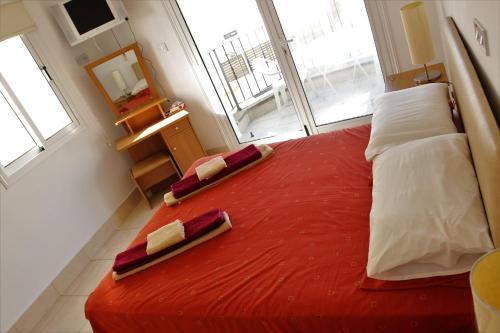 1 dormitorio con 1 cama roja y 2 almohadas en Villa Christina en Pafos