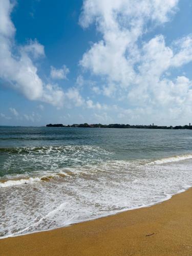 a beach with the ocean on a cloudy day at SENUKi in Galle