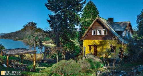 a house on a hill next to a lake at Los Juncos Patagonian Lake House in San Carlos de Bariloche