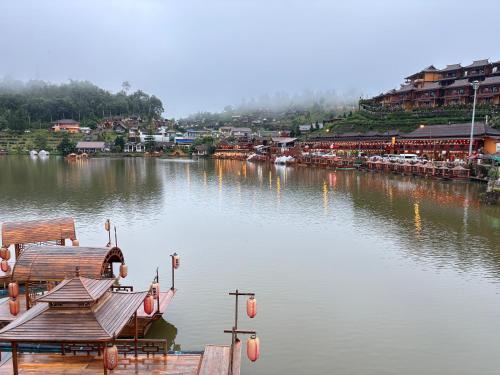 a view of a river with a town in the background at ม่านหมอก รักไทย ManMork RakThai in Ban Rak Thai