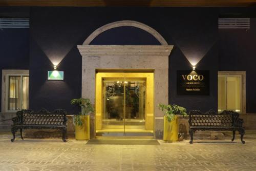 a store front with two benches and a yellow door at voco Saltillo Suites by IHG in Saltillo