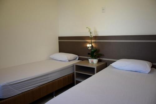 a bedroom with two beds and a night stand with a plant at Suítes Trindade in Florianópolis