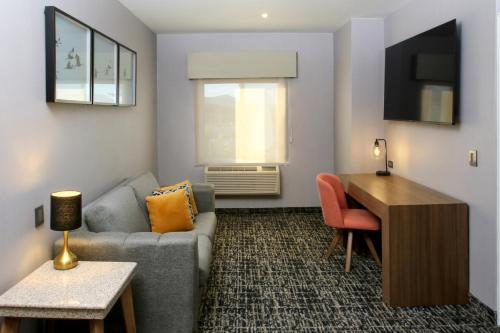 a living room with a couch and a desk at voco Saltillo Suites by IHG in Saltillo