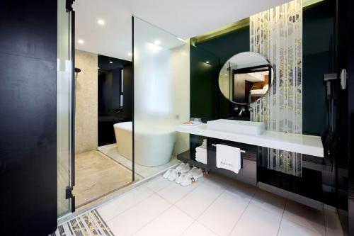 a bathroom with a tub and a sink and a mirror at Xi'an Hotel, Shenzhen Luohu East Gate Yitian Holiday Plaza in Shenzhen