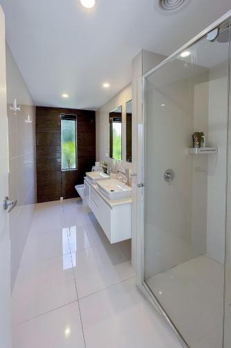 a white bathroom with two sinks and a shower at 4 bedrooms luxury Sea View Family retreat in Sandy bay in Hobart