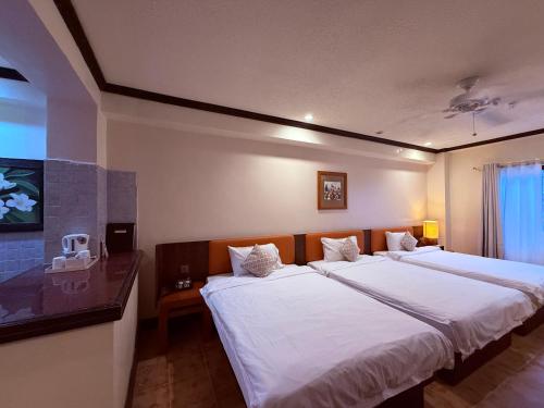 a bedroom with two beds with white sheets at Hanamitsu Hotel & Spa in Garapan