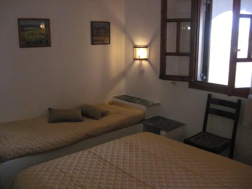 a bedroom with two beds and a chair and a window at Pension Irini-Vicky in Ios Chora
