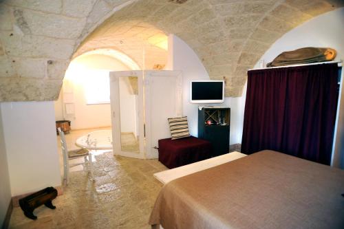 a bedroom with a bed and a room with a tv at Masseria Ancella in Montalbano