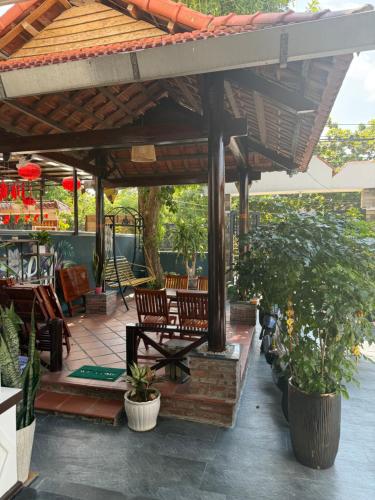 a wooden pavilion with chairs and plants on a patio at Cheerful Hoi An Hostel in Hoi An