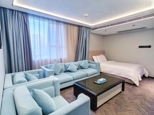 a living room with a couch and a bed at Xi'an Hotel, Shenzhen Luohu East Gate Yitian Holiday Plaza in Shenzhen