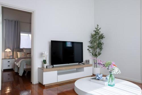 a living room with a flat screen tv on a white cabinet at Lux 4B Queenslander by The Gabba in Brisbane