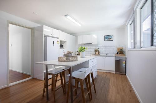 a kitchen with white cabinets and a table and chairs at Lux 4B Queenslander by The Gabba in Brisbane