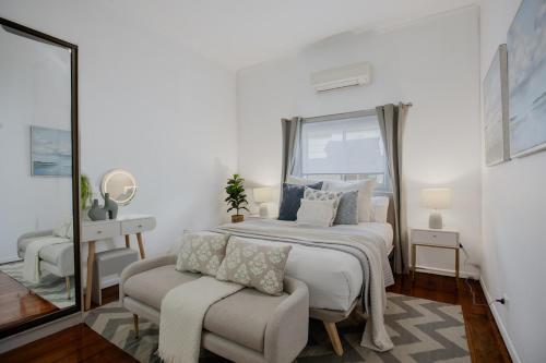 a bedroom with a bed and a chair and a mirror at Lux 4B Queenslander by The Gabba in Brisbane