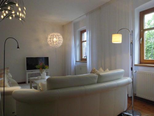 a living room with a white couch and a tv at SchlossparkFerienwohnungen Rheinsberg mit Garten in Rheinsberg
