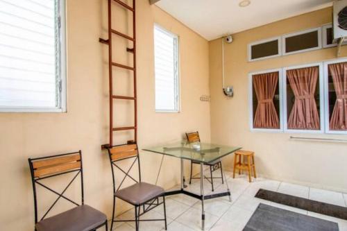 a dining room with a glass table and two chairs at Homestay Helinium RedPartner in Bogor