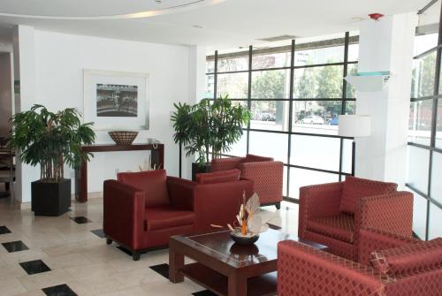 a lobby with chairs and a table and windows at Hotel & Suites PF in Mexico City
