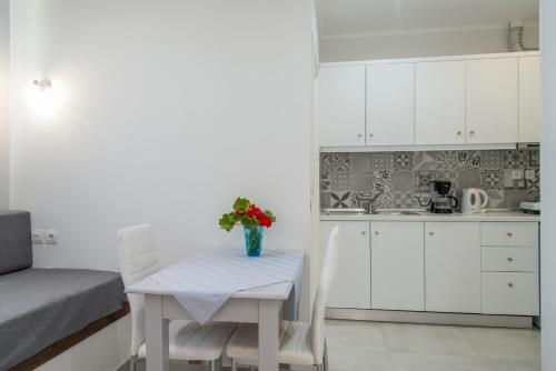 a small kitchen with a table with a vase of flowers on it at Byron Apartments in Tigaki
