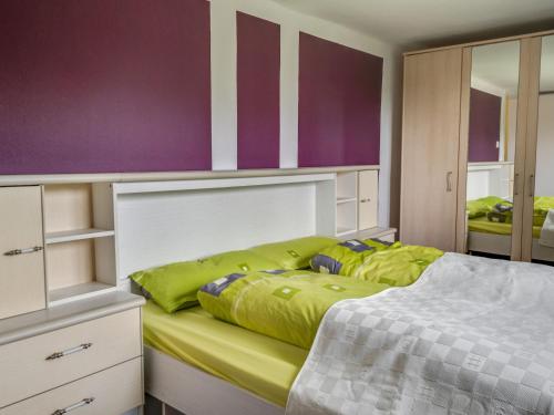 a bedroom with a bed with yellow sheets and purple walls at Cozy Family Apartment in Braunichswalde