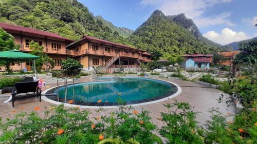 a resort with a pool and mountains in the background at Pác Bó Boutique Hotel in Cao Bằng