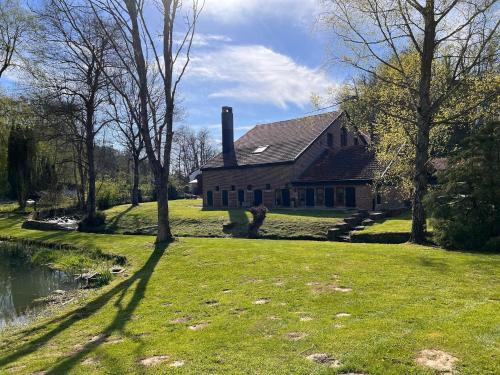 a house on a grassy field next to a pond at Mansion with Pool, Néblon in Ouffet