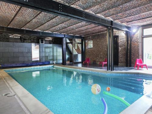 a large swimming pool with blue water in a building at Mansion with Pool, Néblon in Ouffet
