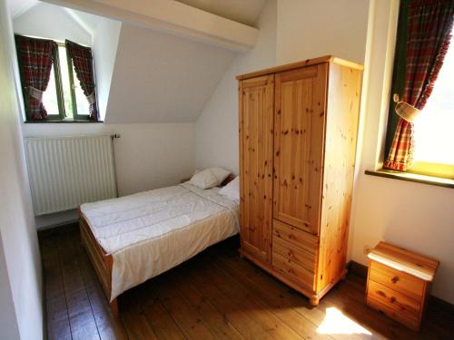 a small bedroom with a bed and a wooden cabinet at Mansion with Pool, Néblon in Ouffet