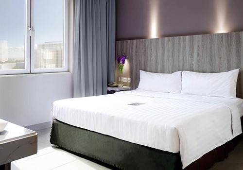 a bedroom with a large white bed and a window at Royal Palm Hotel & Conference Center Cengkareng in Jakarta