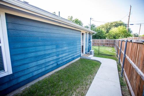 a blue garage door on a house with a fence at Cozy Studio Mins to JPS, Medical City, Historic District, Zoo, Water Garden in Fort Worth