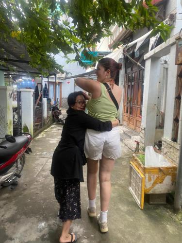 a woman is hugging a woman on a street at Cheerful Hoi An Hostel in Hoi An