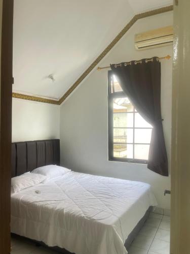 a bedroom with a white bed and a window at Kota bunga in Cikundul