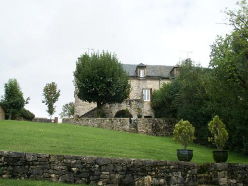 an old stone house with a stone wall and trees at Holiday Home in Saint-Geniez-d'Olt near Lot River in Saint-Geniez-dʼOlt