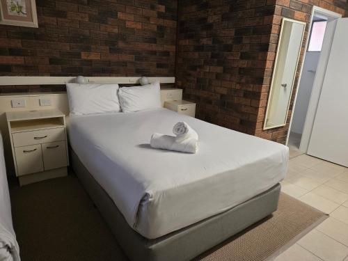a bedroom with a bed with a towel on it at Best Western Parkside Motor Inn in Coffs Harbour