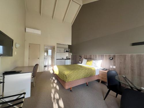 a bedroom with a bed and a desk with a desk at Airport Manor Inn in Auckland
