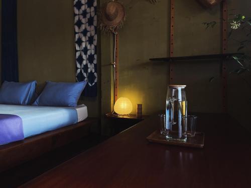 a bedroom with a bed and a table with a blender at Here Library - A wooden home by the river with a library in Thốt Nốt
