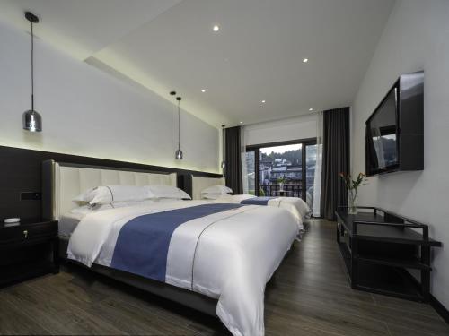 a bedroom with two beds and a flat screen tv at Fenghuang Ancient Town Tinglan Waterfront High-end B&B in Fenghuang