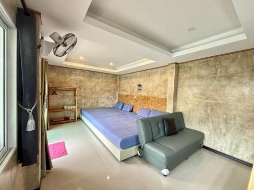 a bedroom with a bed and a green chair at ม่านหมอก รักไทย ManMork RakThai in Ban Rak Thai