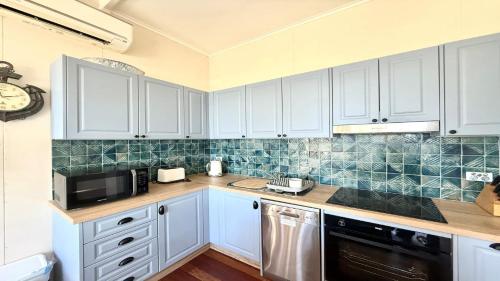 a kitchen with white cabinets and a microwave at Twin Dolphins 1, 1 - 18 Clarence St in Yamba