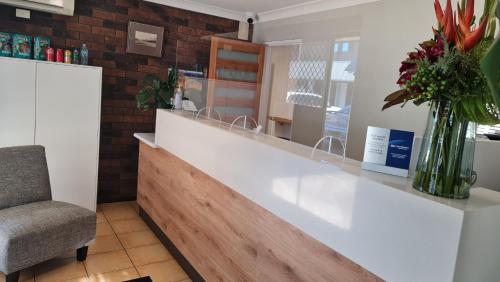 a lobby with a counter with a chair and flowers at Best Western Parkside Motor Inn in Coffs Harbour