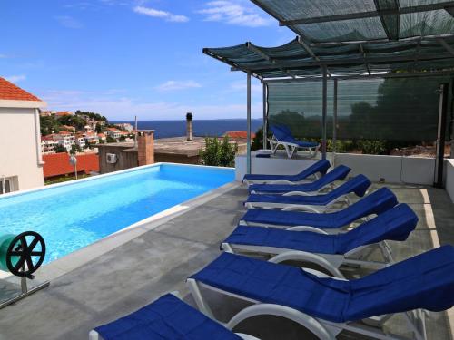 a swimming pool with blue lounge chairs and a swimming poolvisor at Holiday Home in Korcula with Sea View in Zavalatica