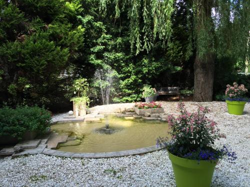 a small pond with a fountain in a garden at Hotel Le Rivage in Olivet
