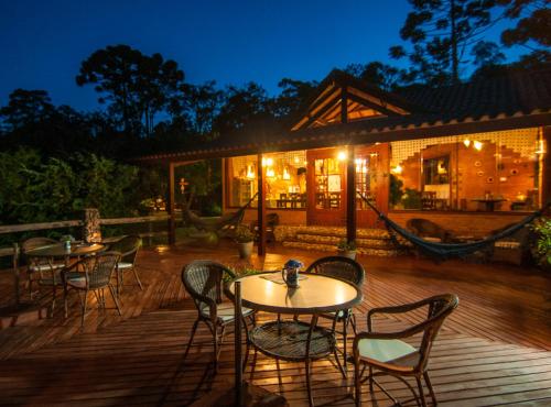 a deck with tables and chairs at night at Pousada Cantinho das Estrelas in Monte Verde