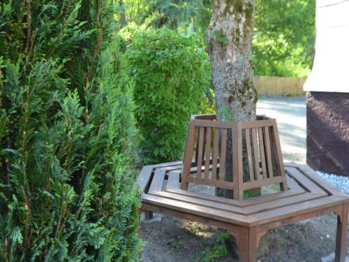 a wooden bench around a tree in a garden at Holiday home in Ramsbeck with garden in Ramsbeck